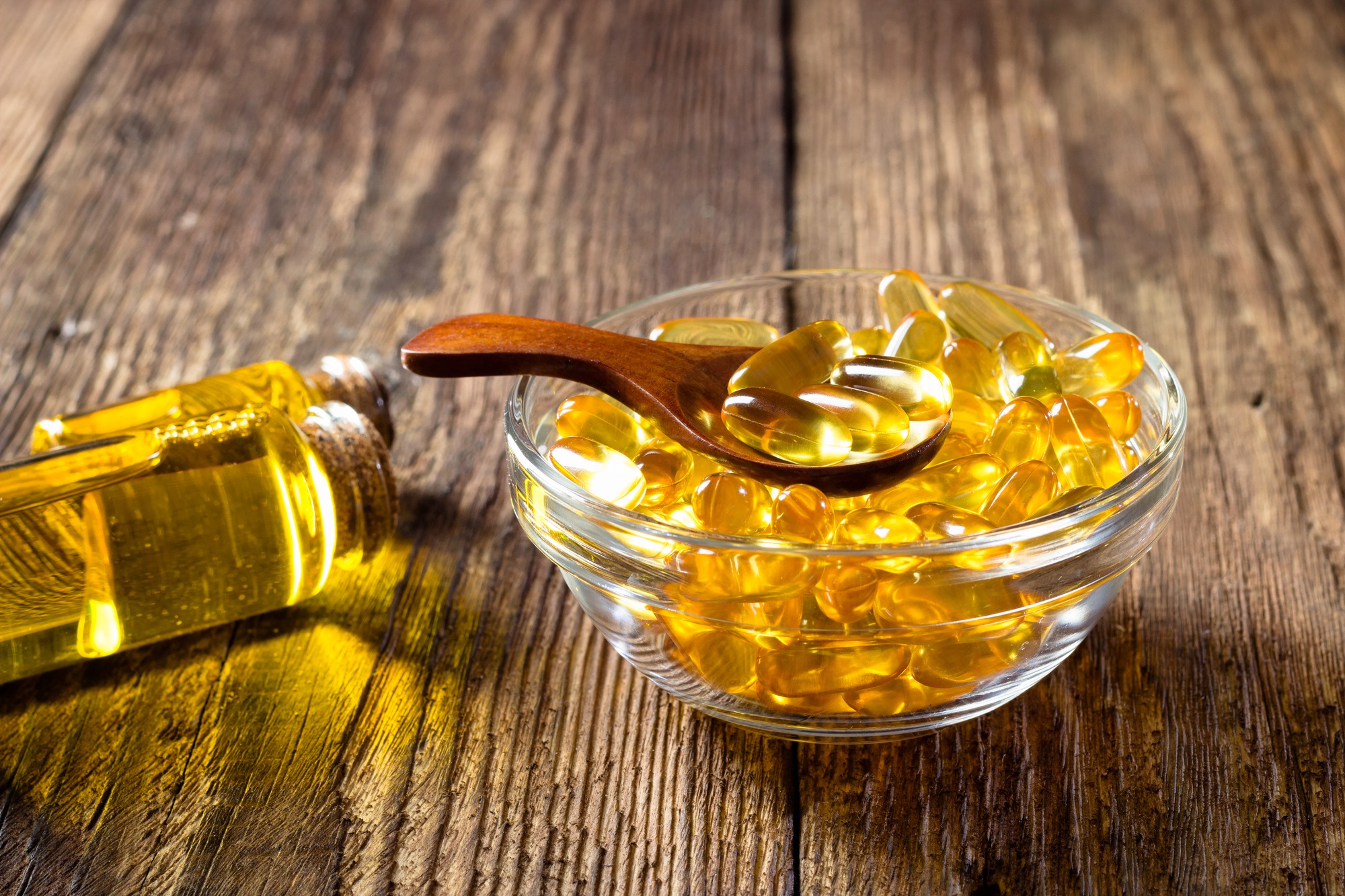 Fish oil capsules on wooden background, vitamin D supplement